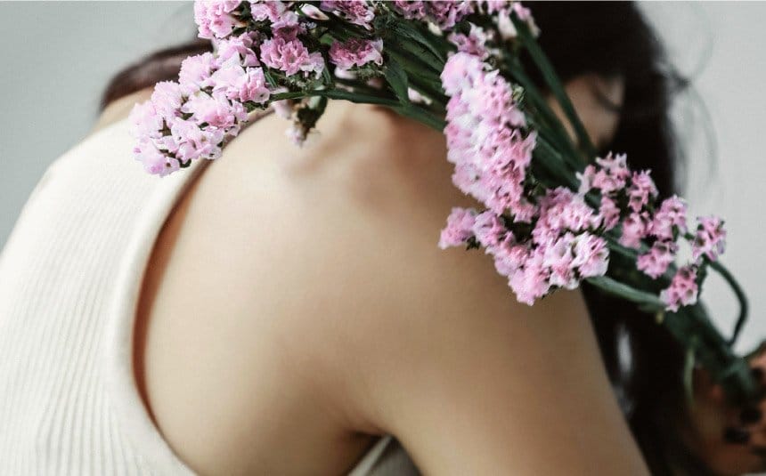 Hombro de mujer con flores, abrazandose a si misma mostrando amor.